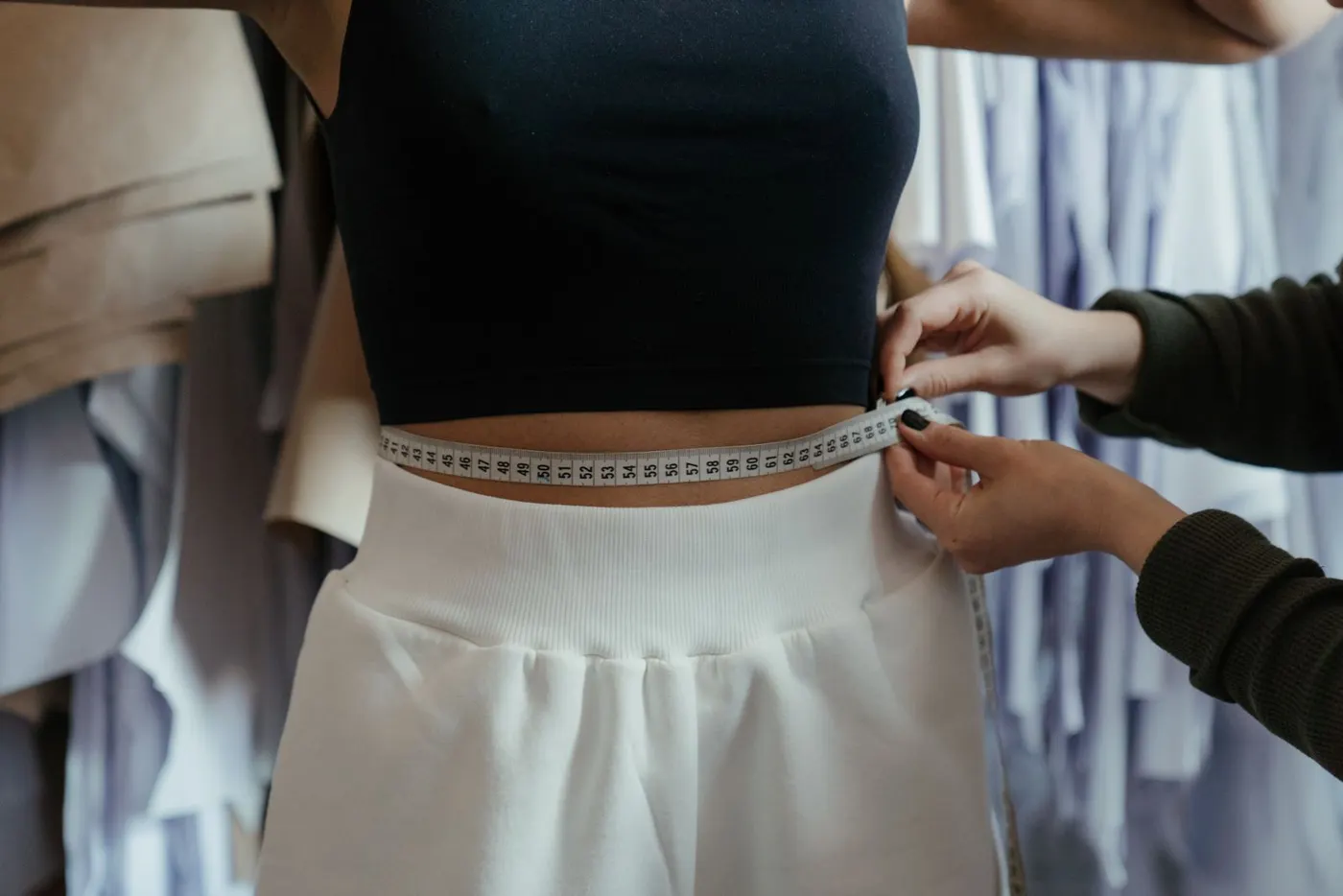 Couturière qui mesure le tour de taille d'une cliente